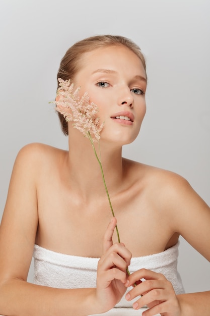 Belle femme blonde avec une peau parfaite et une branche florale