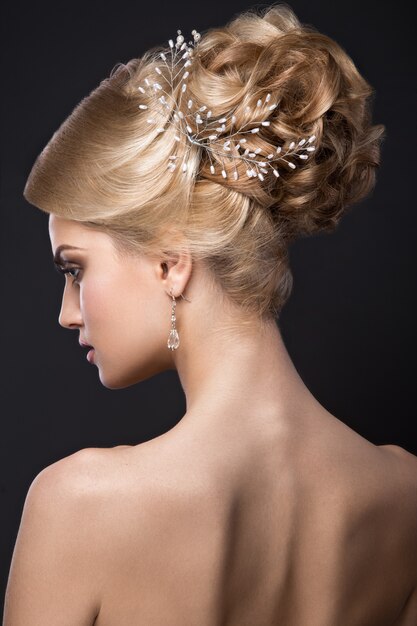 Belle femme blonde avec une peau parfaite, maquillage de soirée, coiffure de mariage et accessoires