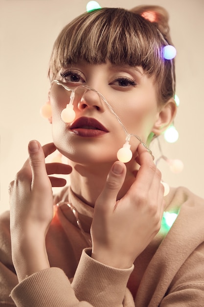 Belle femme blonde positive avec des lumières de Noël sur la tête