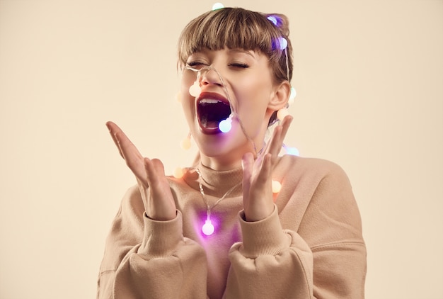 Belle femme blonde positive avec des lumières de Noël sur la tête