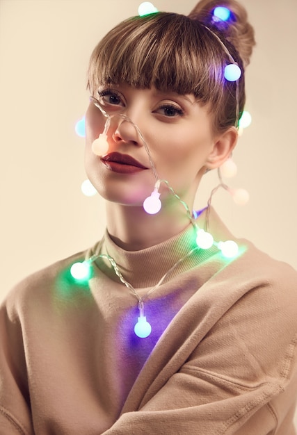 Belle femme blonde positive avec des lumières de Noël sur la tête