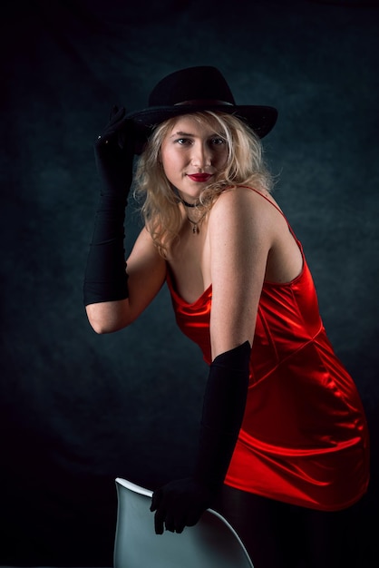 Belle femme blonde en robe de soirée élégante rouge et chapeau noir