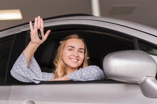 Belle femme blonde saluant d'une voiture