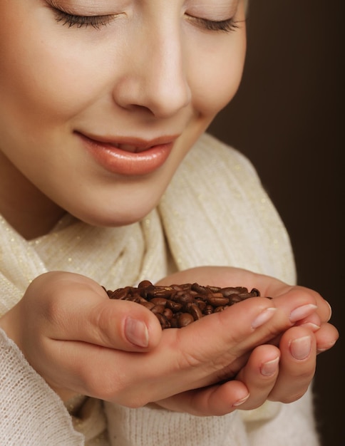 Belle femme blonde sentant les grains de café