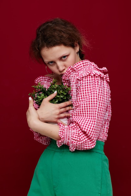 Photo belle femme en blouse rose pose avec une plante en pot blanc