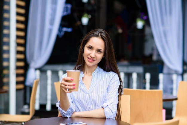 Belle femme boit du café dans un café de la rue.