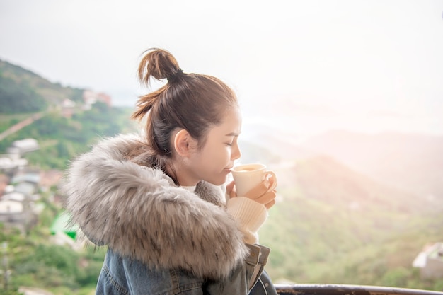 Belle femme boit du café le matin avec fond de nature