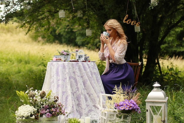 belle femme boit du thé de tasse de thé vintage dans la nature.