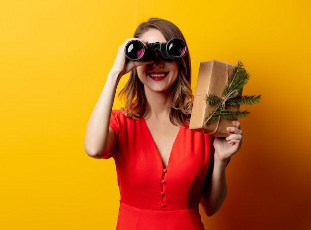 Belle femme avec une boîte-cadeau et des jumelles