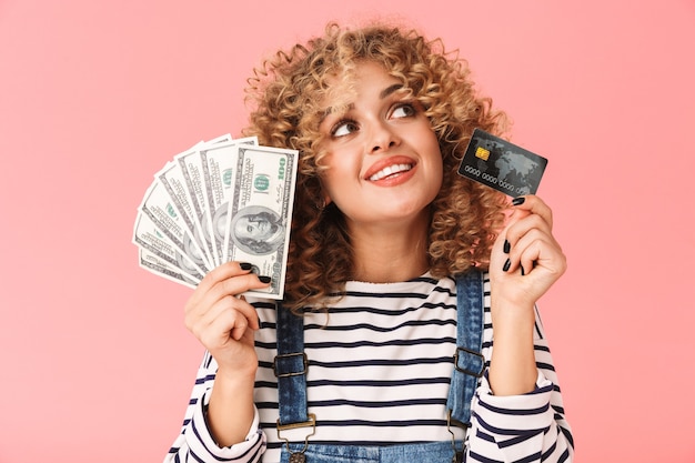 Belle femme bouclée des années 20 tenant fan d'argent dollar et carte de crédit en position debout