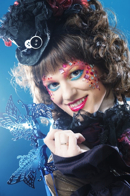 Belle femme bouclée avec masque. Visage de carnaval. Photo de vacances.