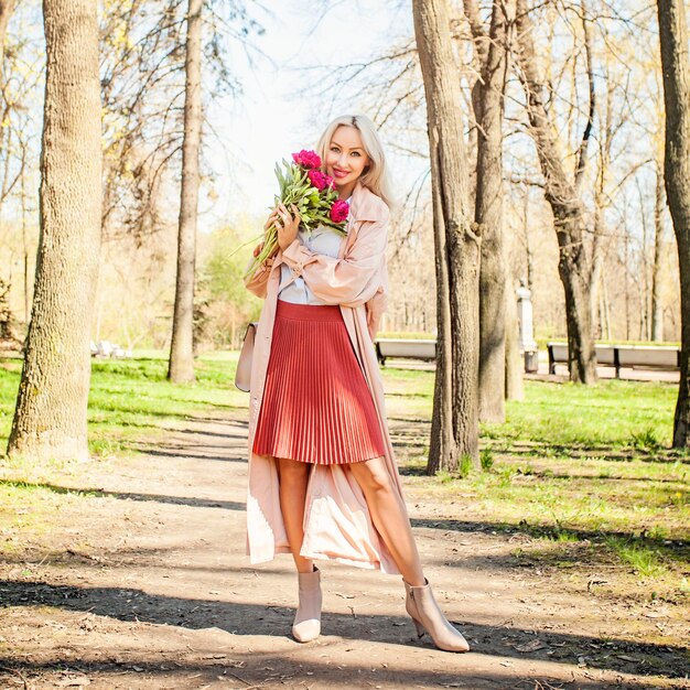 Belle femme avec bouquet de fleurs à l'extérieur Modèle féminin avec pivoine dans le parc