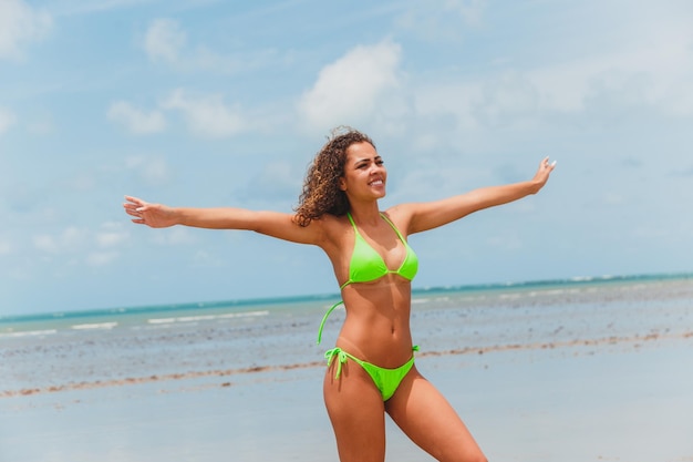 Belle femme brésilienne afro sur une plage de rio grande do norte a souri en sentant la liberté et les vagues de la mer profitant de ses vacances d'été avec un soleil et une chaleur merveilleux