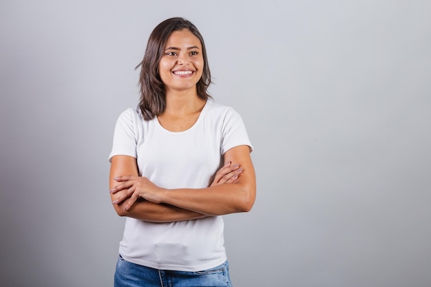 Belle femme brésilienne avec les bras croisés denim et blanc souriant optimiste