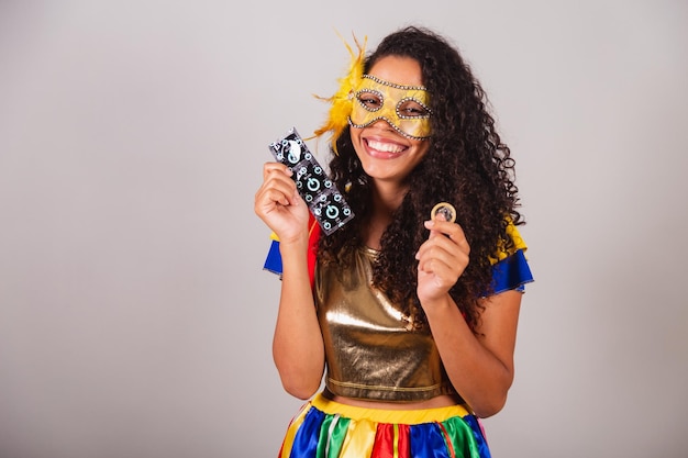 Belle femme brésilienne noire avec carnaval de vêtements frevo portant un masque tenant un préservatif lutte contre le sida