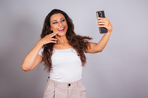 Belle femme brésilienne tenant un smartphone faisant un autoportrait Selfie