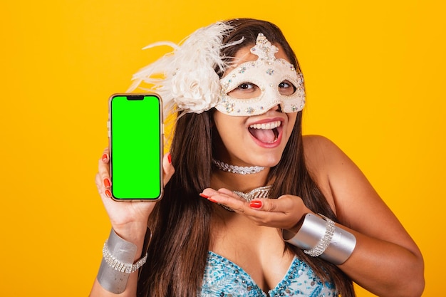 Belle femme brésilienne en vêtements de carnaval bleu et blanc tenant un smartphone avec écran vert