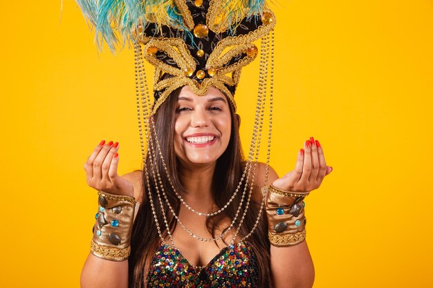 Belle femme brésilienne en vêtements de carnaval doré portant une couronne de plumes de danseuse de carnaval invitant avec les mains