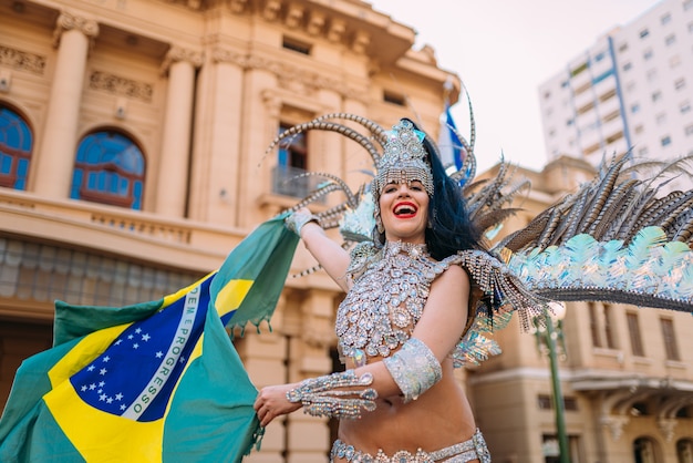 Belle femme brésilienne vêtue d'un costume de carnaval coloré et d'un drapeau brésilien pendant le défilé de rue du Carnaval en ville.