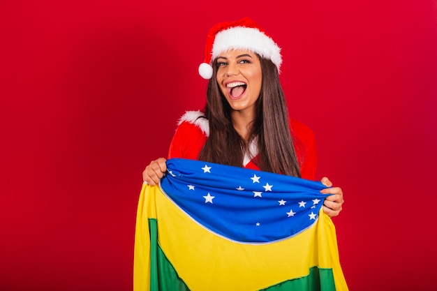 Belle femme brésilienne vêtue de vêtements de Noël Père Noël avec le drapeau du Brésil