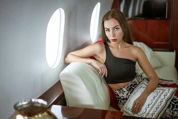 Belle femme brune assise dans un siège d'avion privé