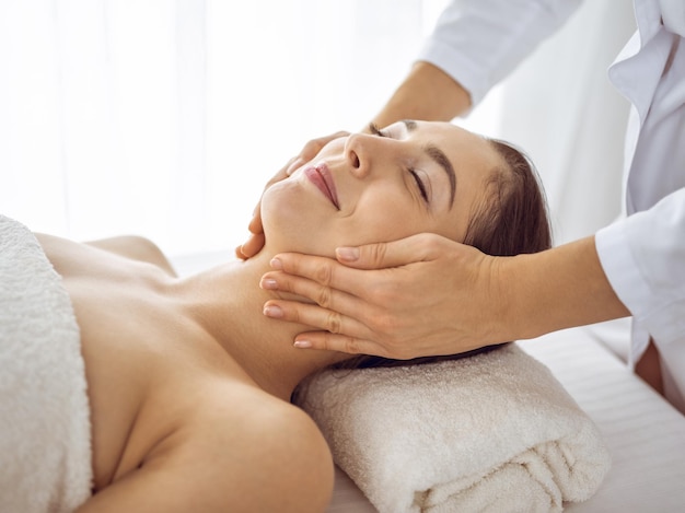 Belle femme brune bénéficiant d'un massage facial avec les yeux fermés. Traitement relaxant dans les concepts de centre de médecine et de spa.