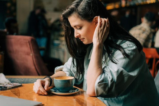 Une belle femme brune boit du café dans un café.