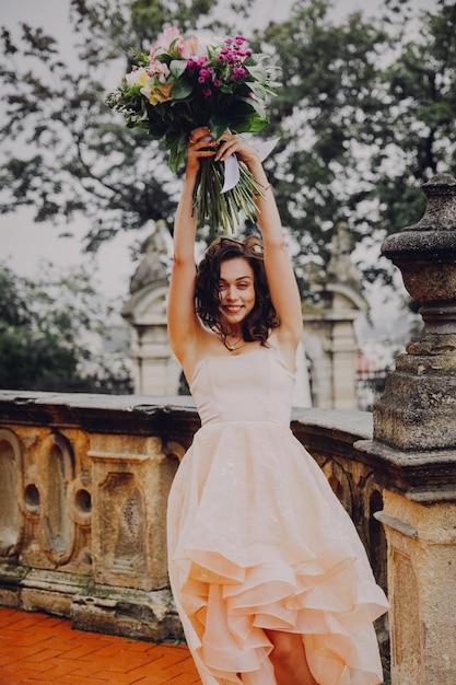 Belle femme brune avec un bouquet de fleurs dans une robe rose