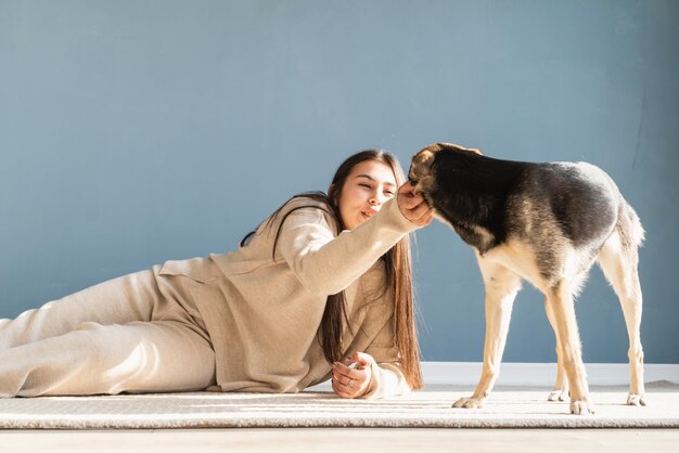 Photo une belle femme brune avec un chien de race mixte ludique s'embrassant et s'amusant à la maison