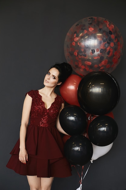 Belle femme brune dans une robe rouge avec des ballons