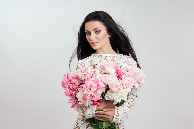 Belle femme brune avec des fleurs de pivoine