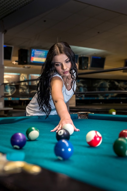 Belle femme brune jouant au billard dans un pub