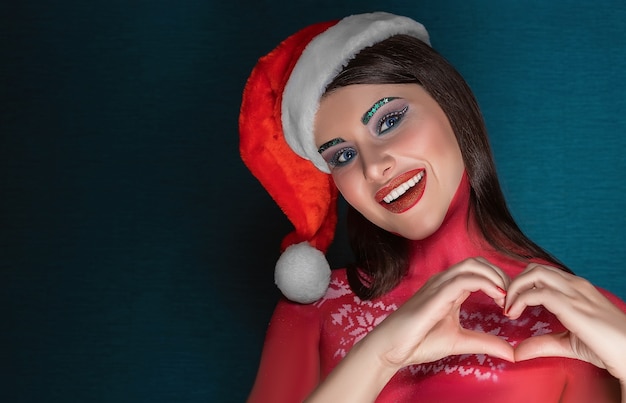 Belle femme brune avec maquillage art créatif portant chapeau de père Noël souriant