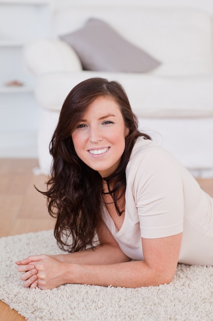 Belle femme brune posant en position couchée sur un tapis