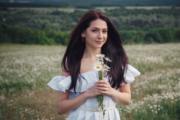 Belle femme brune profite du printemps dans un champ de marguerites