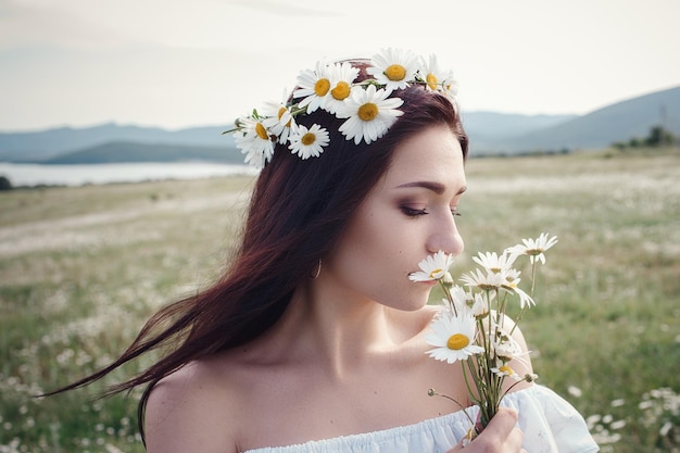 Belle femme brune profite du printemps dans un champ de marguerites