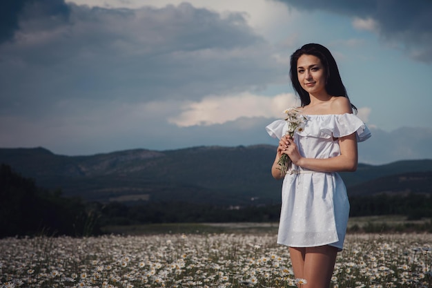 Belle femme brune profite du printemps dans un champ de marguerites