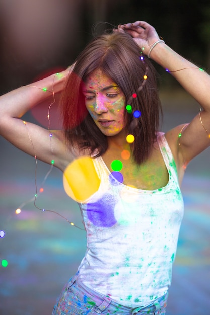 Belle femme brune recouverte de poudre sèche Holi et tenant une guirlande