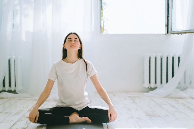 Belle femme brune de remise en forme méditer, faire du yoga à l'intérieur à la maison