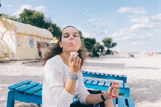 Belle femme et bulles de savon sur la plage