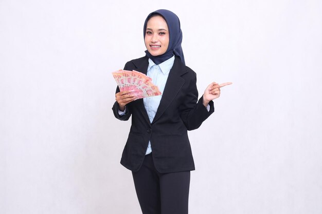 Une belle femme de bureau asiatique portant un hijab se tient heureuse pointant vers la gauche et portant un rupi