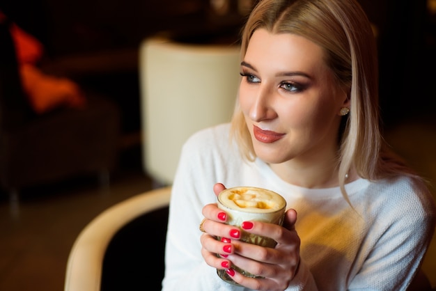 Belle femme buvant un cappuccino dans un café