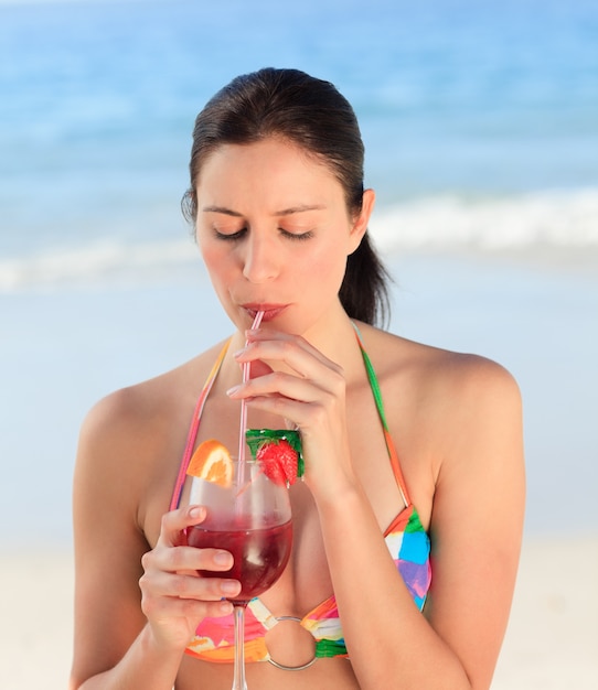 Belle femme buvant un cocktail sur la plage