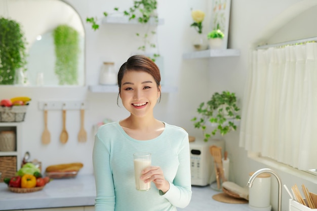 Belle femme buvant du lait dans la cuisine à la maison