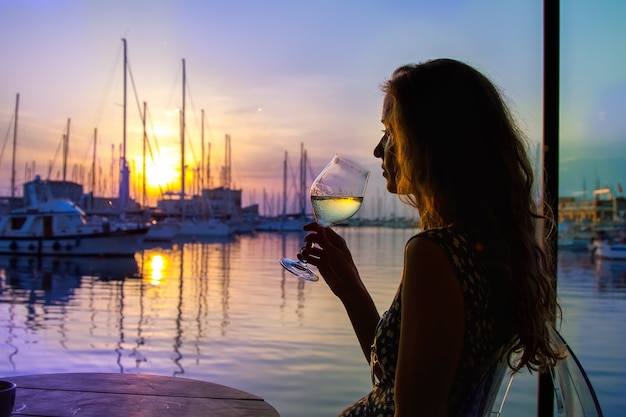 La Belle Femme Buvant Du Vin Et Regardant Un Déclin Du Soleil