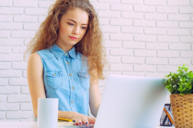 Belle femme caucasienne assise et travaillant sur un ordinateur portable