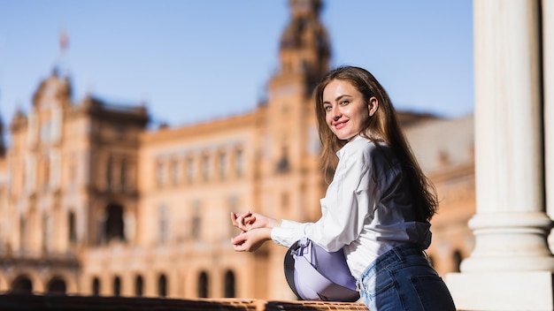 Belle femme caucasienne souriante s'appuyant sur une balustrade de balcon visitant la Plaza de España à Séville