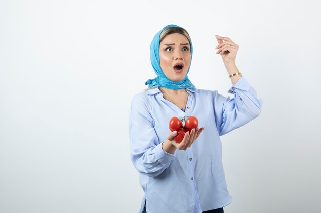 Belle femme en châle bleu tenant des tomates fraîches rouges