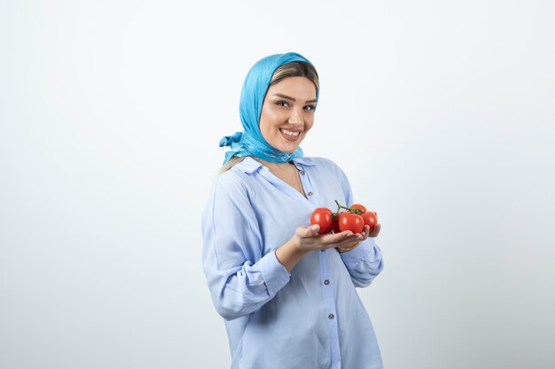 Belle femme en châle bleu tenant des tomates fraîches rouges