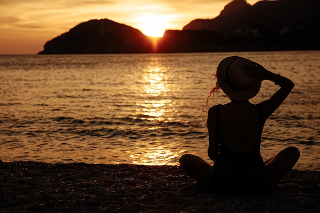 Photo belle femme avec un chapeau près de la mer